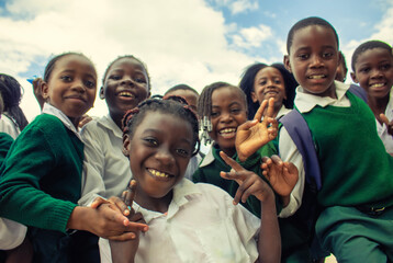 Real photo of happy black African kids in school uniforms, smiling and enjoying a break. A positive image of youth, education, diversity, and community spirit.