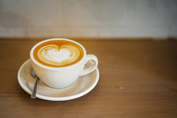 Top of hot latte coffee with latte art in a white cup on wooden table