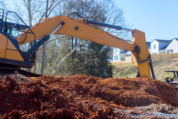 Heavy machinery performs excavation at construction site as homes overlook work area