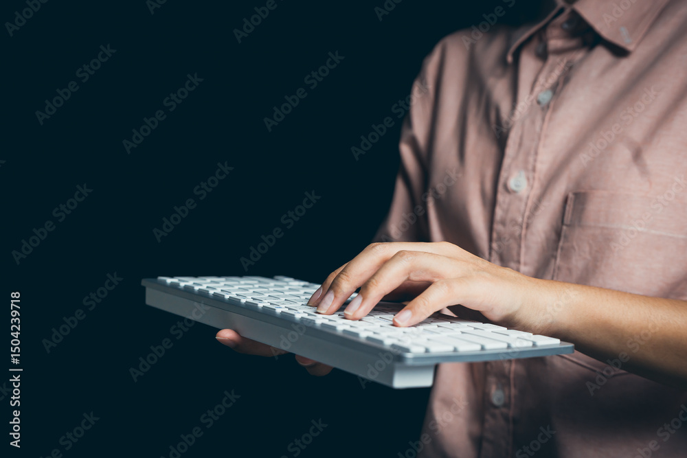Poster close-up of a hand operating a computer keyboard in a low-light environment with dark background