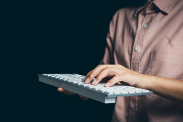 Close-Up of a Hand Operating a Computer Keyboard in a Low-Light Environment with Dark Background