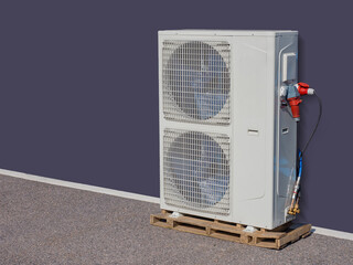 Industrial outdoor air conditioning unit with dual fans mounted on a wooden pallet and connected to...