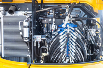 Fototapeta premium Close-up of hydraulic system and hoses inside heavy machinery, showing complex hydraulic connections, valves, and cooling system. – Machinery Maintenance, Construction Equipment.