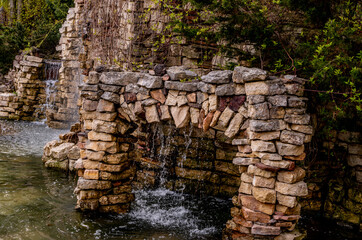 An artificial waterfall in the park among the rocks.