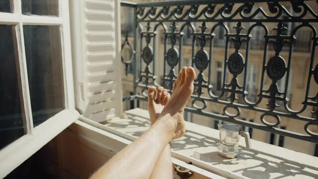 Woman relaxing with feet up on balcony railing, enjoying cityscape view