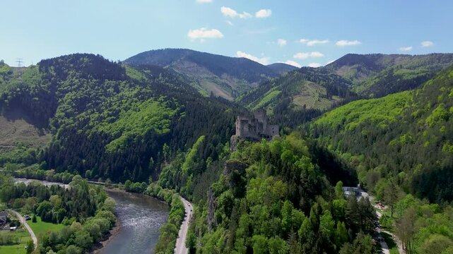 Drone footage reveals the majestic ruins of Strečno Castle perched dramatically on a limestone cliff above the V&aacute;h River, surrounded by the lush, mountainous forests of northern Slovakia