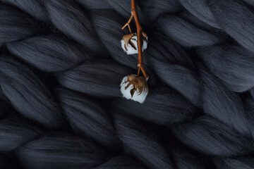 a branch of cotton on a background of a gray merino wool blanket