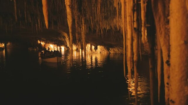 tourist boat approaching underground cave lake with stalactites