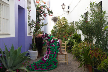 Young and beautiful woman dancing flamenco rests one foot on an old wooden chair in a typical...