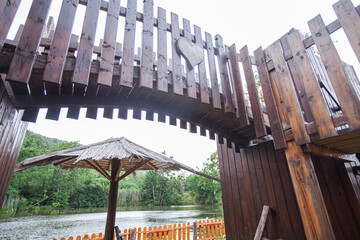 Wooden Curved Bridge Architecture With Geometric Design Over Water In Lakeside Park Setting