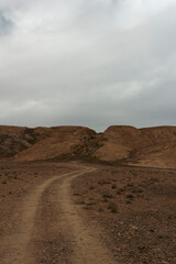 A rugged mountain landscape near Taft, Yazd, Iran, with steep slopes and rocky terrain under a dramatic sky, highlighting the raw beauty of nature.