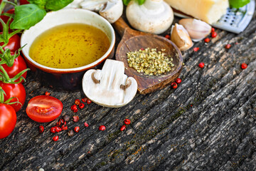 Close up of different ingredients for cooking Italian food. Cherry tomatoes mushrooms parmesan cheese garlic olive oil basil and spices on rustic dark wooden table with copy space