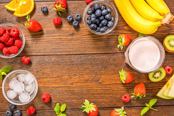 Flat lay of smoothie with fresh ingredients for preparation and ice cubes on rustic wooden table top view with copy space