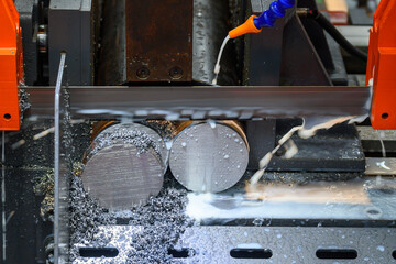 The band saw cutting machine cutting the group of metal shaft parts with coolant method.