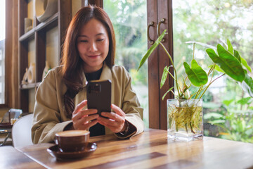 Portrait image of a woman holding and using mobile phone in cafe