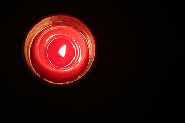 a red candle in a transparent glass burns and creates a cozy light