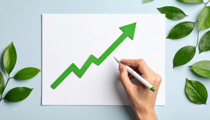 Green arrow graph eco investing stocks concept with hand holding pen and leaves on blue background for growth and success