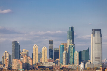 Panoramic view of Lower Manhattan skyline featuring One World Trade Center, seen from across the Hudson River on a clear day in New York City.