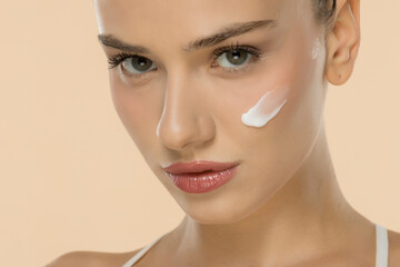 Close-up of woman with white skincare product swatch, showcasing natural beauty and smooth skin...