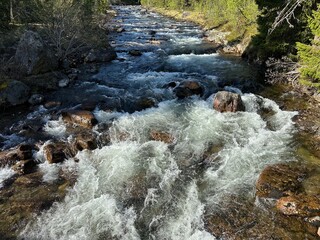 Crystal clear river with its powerful current rushes through a rocky landscape in north Sweden.