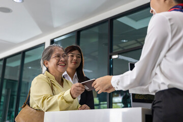 Asian senior passenger is showing their boarding pass to the airline ground crew at departure gate into the airplane for final inspection before boarding into plane