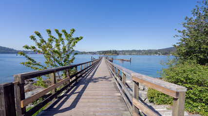 Wooden pier leading to fishing platform at Belcarra public park, BC, Canada, with stunning views across Burrard Inlet to town of Deep Cove.