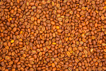 Macro shot of roasted coffee beans, showcasing their deep brown hues and cracked surfaces in a dense arrangement. Ideal for gourmet food and beverage photography.