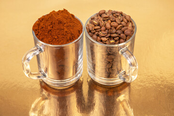 Close-up of two glass mugs on a golden background , one packed with whole roasted coffee beans, the other with rich coffee grounds. Ideal for culinary or beverage concepts