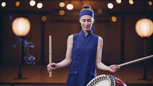 Woman playing traditional taiko drum with sticks in cultural setting  