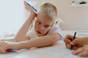 A loving mother and her son work together on homework at the kitchen table, symbolizing family support, education, and care. The scene highlights the importance of parental guidance