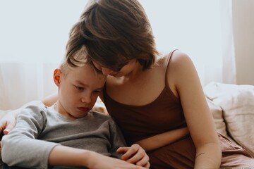 Mother and son playing guitar together, family love. The child wears a hearing aid, highlighting...