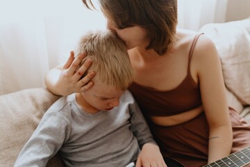 Mother and son playing guitar together, family love. The child wears a hearing aid, highlighting...
