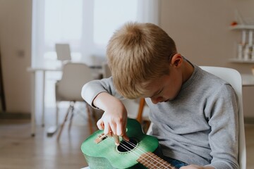 Mother and son playing guitar together, family love. The child wears a hearing aid, highlighting...