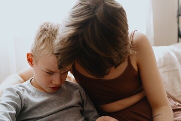 Mother and son playing guitar together, family love. The child wears a hearing aid, highlighting...