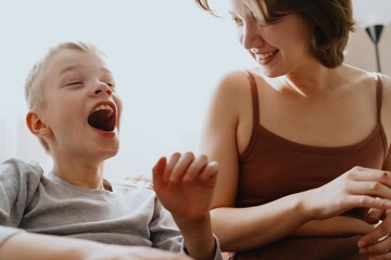 Mother and son playing guitar together, family love. The child wears a hearing aid, highlighting...