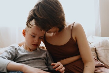 Mother and son playing guitar together, family love. The child wears a hearing aid, highlighting...