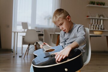 Mother and son playing guitar together, family love. The child wears a hearing aid, highlighting...