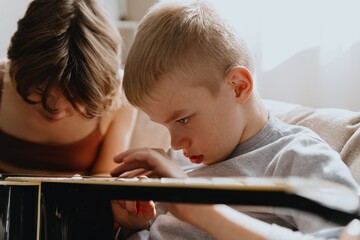 Mother and son playing guitar together, family love. The child wears a hearing aid, highlighting...