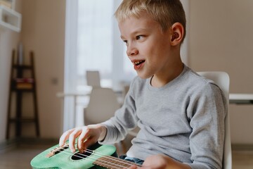 Mother and son playing guitar together, family love. The child wears a hearing aid, highlighting...