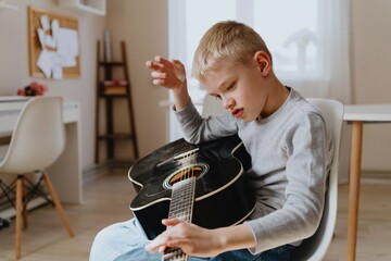 Mother and son playing guitar together, family love. The child wears a hearing aid, highlighting...