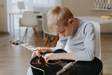 Mother and son playing guitar together, family love. The child wears a hearing aid, highlighting...