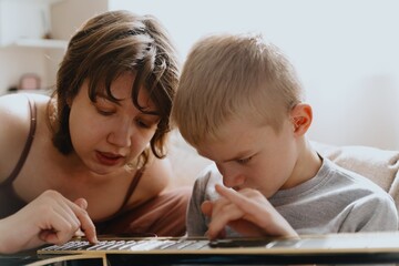 Mother and son playing guitar together, family love. The child wears a hearing aid, highlighting...