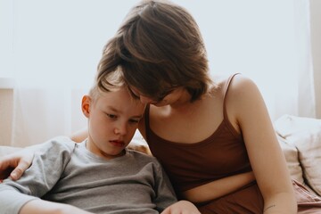 Obraz premium Mother and son playing guitar together, family love. The child wears a hearing aid, highlighting inclusivity and the universal language of music. Authentic, unedited photo captures emotions