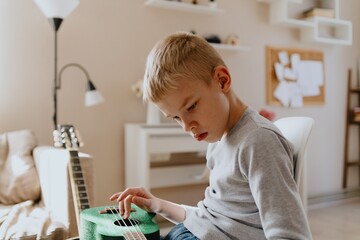Mother and son playing guitar together, family love. The child wears a hearing aid, highlighting...