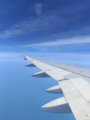 Airplane wing with beautiful clouds and blue sky view from window