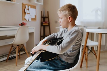 Mother and son playing guitar together, family love. The child wears a hearing aid, highlighting...