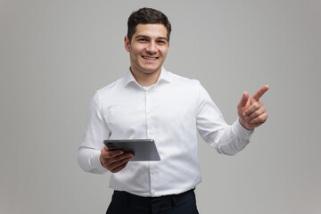Smiling man enthusiastically gestures while holding a tablet in a modern indoor setting during...