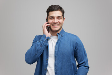 Cheerful young man engages in conversation on smartphone with a bright smile in a modern setting