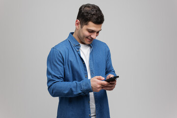 Young man engaged in joyful moment while texting on smartphone in modern indoor setting