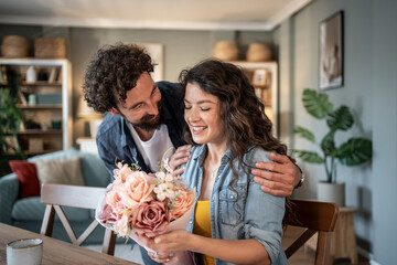 Man giving flowers to woman at home: romantic surprise
